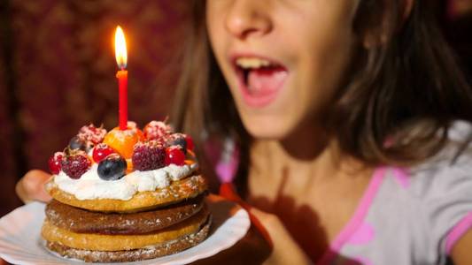 小女孩的生日她在蛋糕上吹蜡烛图片