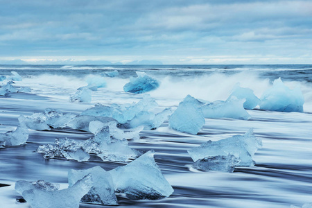 在冰岛南部的梦幻般的海滩与黑色熔岩沙子充满冰山从冰川。冬天