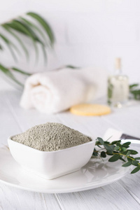 干面粘土粉在碗里。用于家庭或沙龙水疗的天然化妆品白色背景处理