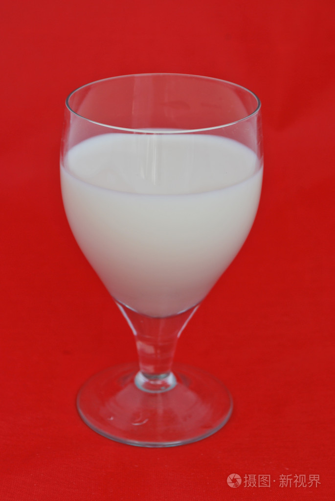 杯新鲜的牛奶被隔绝在红色背景上