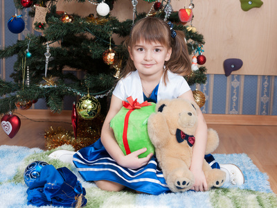 在圣诞树上带圣诞礼物的微笑女孩6年
