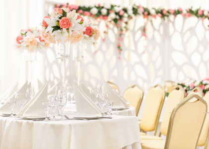 配表事件晚餐餐具和杯子，粉色和珊瑚色调装饰花瓶中的花组成
