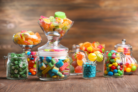放在桌上木制的背景上的罐子里的糖果色彩在一根棍子上的糖果棒棒糖