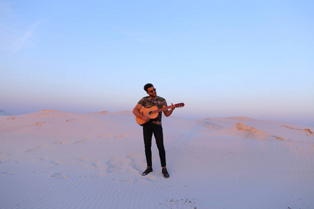 英俊的男性阿拉伯玩吉他站在中间的无底洞