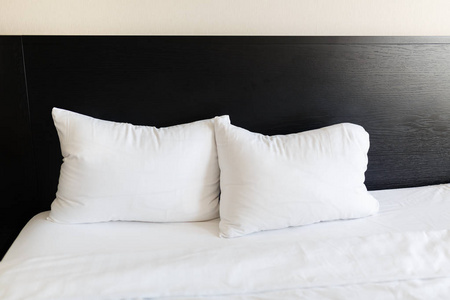 床用的黑背上的白色枕头。用干净的白色枕头和床单在房间里的床。特写
