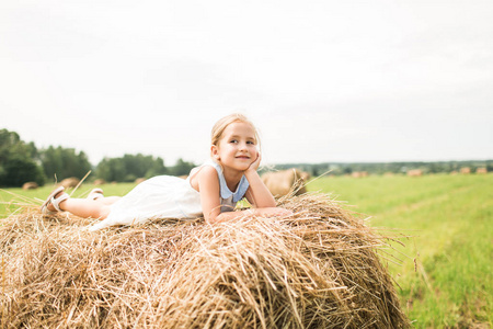 小女孩坐在干草堆里，一个夏天的概念