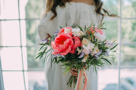 新娘手里拿着的乡村婚礼花束白玫瑰与窗口背景上的深红色牡丹。特写