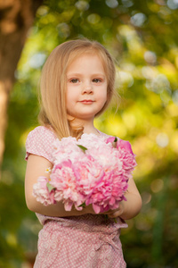 漂亮的女婴,与粉红色的花朵在户外.2-3 岁的小女孩照片