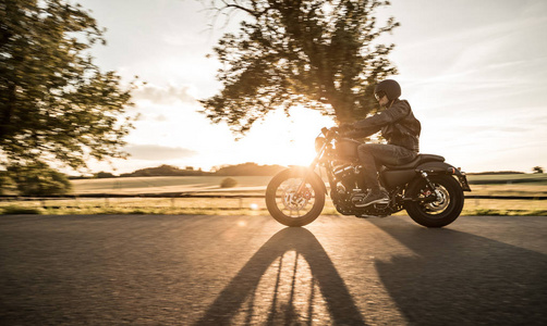 在日落期间骑 sportster 摩托车的男子照片