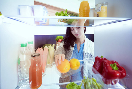 女性站附近打开冰箱充分的健康食品，蔬菜和水果的画像。女性肖像