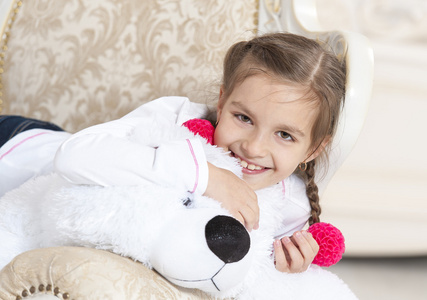 快乐的女孩，在扶手椅上的玩具熊