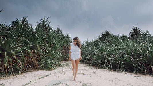 小女孩站在海滩上的外来植物背景