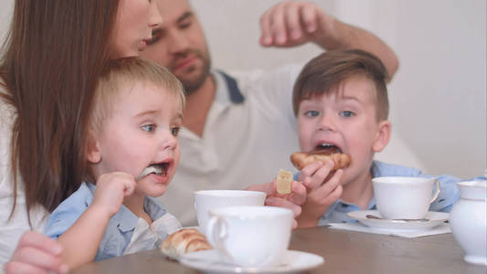 两个男孩的小孩子和糕点和父母一起喝茶