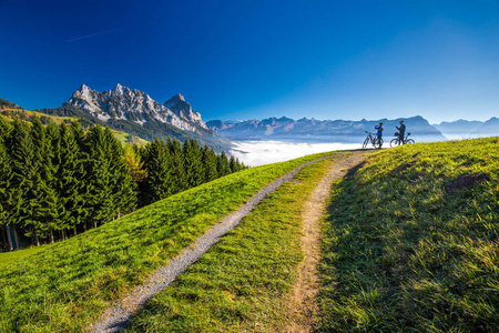 两个骑自行车的人看着 Mythen 在瑞士阿尔卑斯山的山峰
