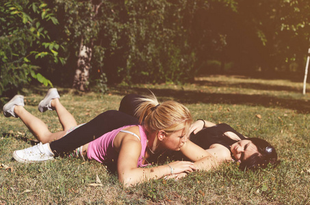 两个年轻的姐妹躺在草地上, 在公园里放松