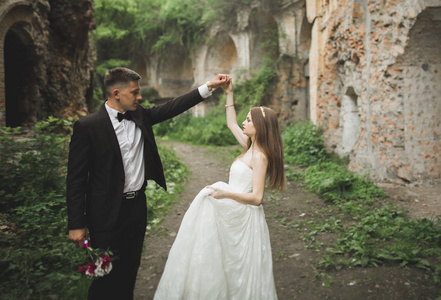 美丽浪漫新婚夫妇的新婚夫妇拥抱在旧城堡附近