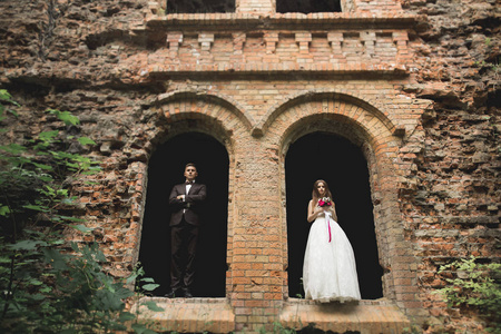 刚刚结婚的姿势和亲吻与背景上古老的城堡
