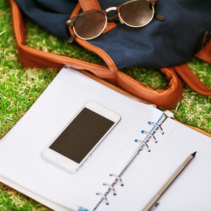 现代数字笔记本与手机的智能手机，在绿色草地上