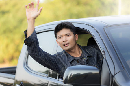 年轻男子在车里显示他的手来求救。生活方式的概念