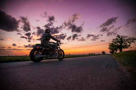 在日落期间骑 sportster 摩托车的男子