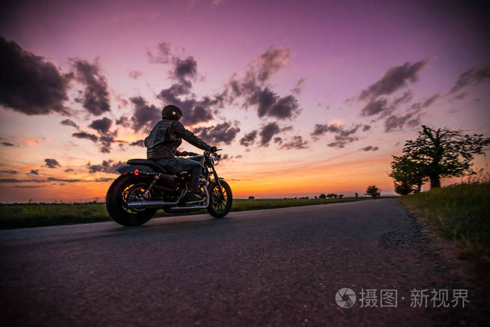 在日落期间骑 sportster 摩托车的男子