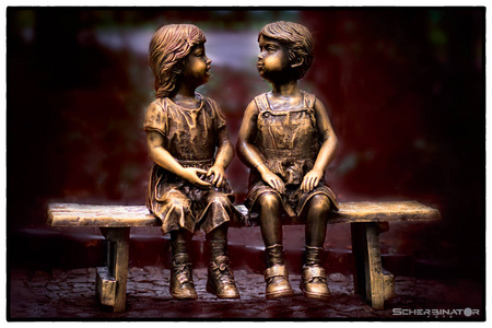 雕塑小男孩和女孩坐在长凳上自然