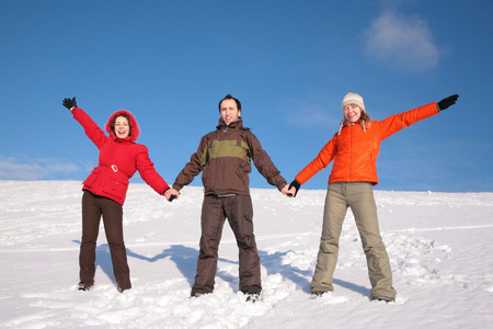 三个朋友站在山坡上的雪上