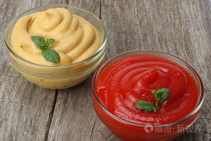 在玻璃碗里木背景上的芥末番茄酱表