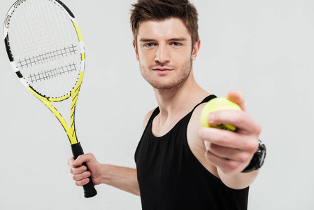 英俊的年轻运动员举行网球球和球拍