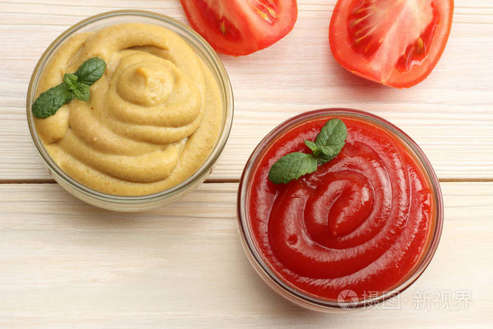 在玻璃碗里木背景上的芥末番茄酱表