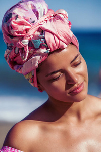 在海滩上穿粉色头巾的美丽和平静的女人肖像