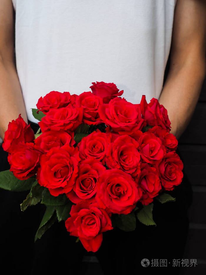 男性的人拿着一束美丽的红玫瑰穿 whi