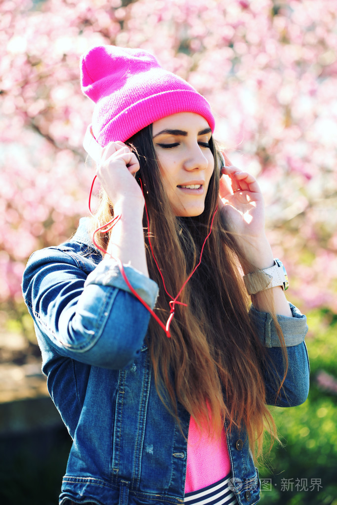 的一个有趣的年轻赃物女孩在茂盛花园在听音乐的耳机从智能手机 mp3