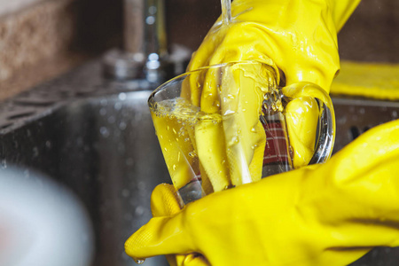在黄色橡胶手套的手洗茶杯图片