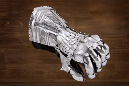 中世纪的盔甲,古代盔甲的细节.钢手套上木制背景照片