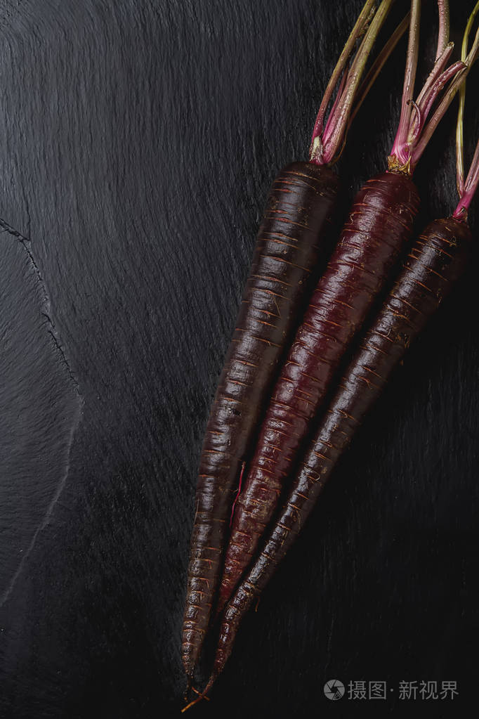 成熟的黑色胡萝卜.黑石头的背景.秋天的收获.顶尖 v