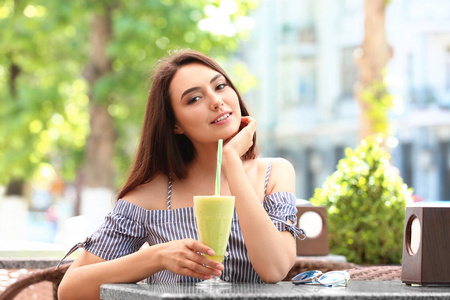 年轻漂亮的女人喝冰沙在咖啡馆