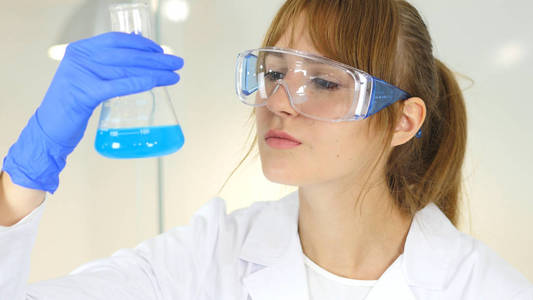 女科学家控股，看着蓝色溶液在烧瓶中实验室
