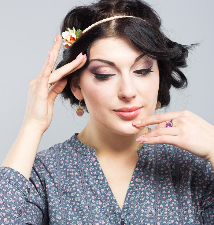 一个年轻的姑娘在灰色的背景上的肖像.希腊的发型黑发