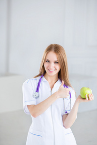 医生抱着一个绿色的苹果。健康食品的概念