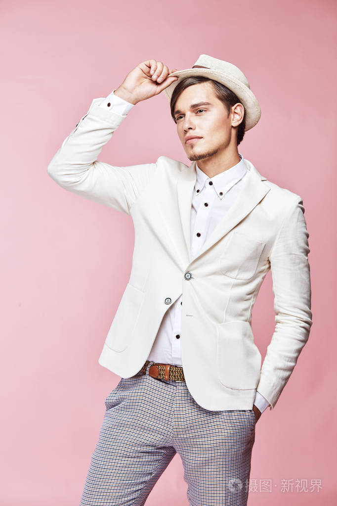 年轻美丽快乐严重现代男模特穿着白色夹克, 白衬衫, 灰色的裤子和白色