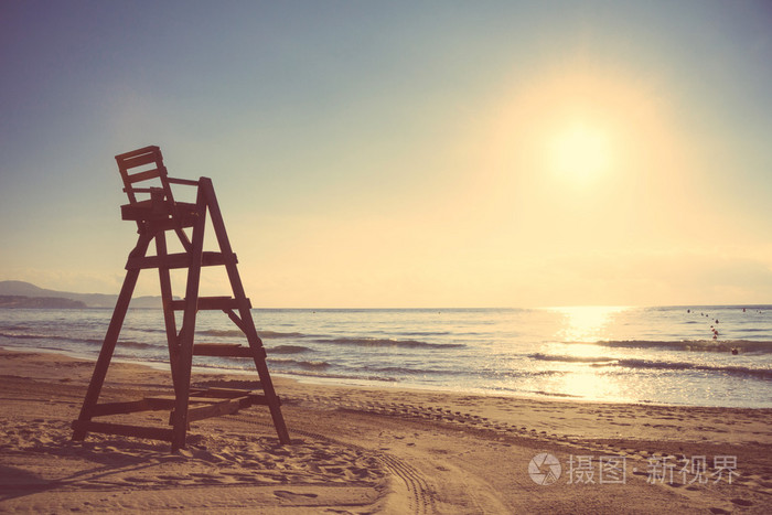 在空旷的海滩，在日落时的救护队椅子