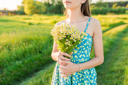 一个年轻的女孩穿着蓝色的衣服手里拿一束野花