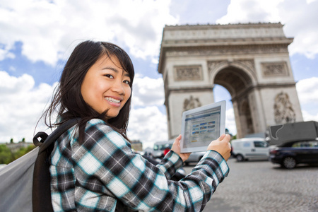 在巴黎使用平板电脑的年轻诱人的亚洲旅游