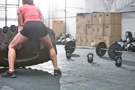 女人在运动量来找到健身房翻转轮胎