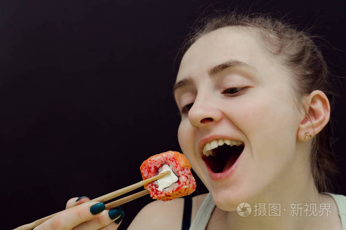 女人用筷子吃面包.张开嘴巴.黑色背景