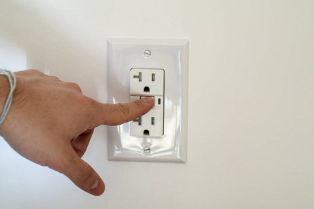 手指危险接近电插座。触电和电击的风险