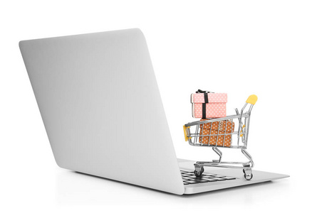 笔记本电脑和小购物车与礼品盒在白色背景。网络购物理念