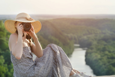 夏装的女孩, 戴着照相机的帽子。绿色森林和河在距离