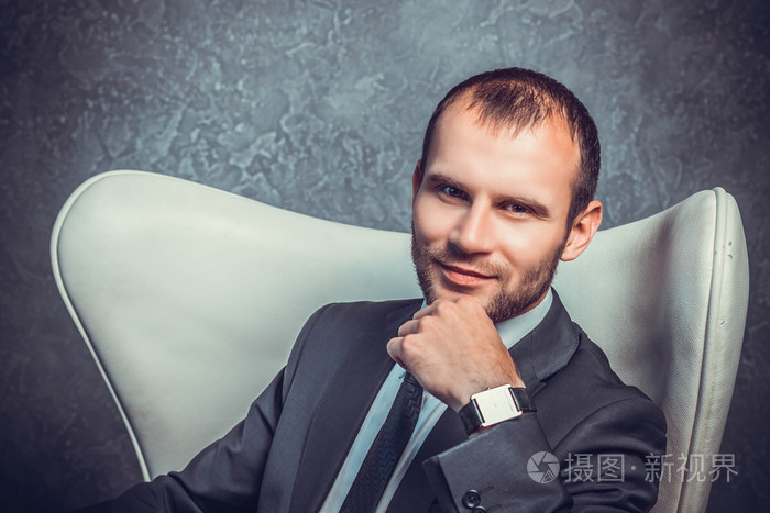 残酷的性感商人穿西装打领带,坐在椅子上.老板的概念